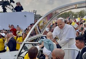 Le pape Léon XIV bénit un bébé présenté par une bénévole lors de son arrivée place de la Concorde à Paris.