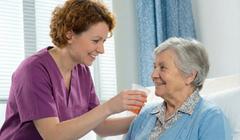 Une soignante donne à boire à une personne en soins palliatifs