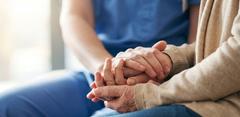 Une soignante tient les mains d'une personne âgée