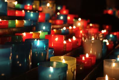 Rangées de bougies votives multicolores allumées dans une église
