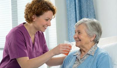 Une soignante donne à boire à une personne en soins palliatifs