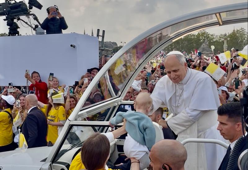 Le pape Léon XIV bénit un bébé présenté par une bénévole lors de son arrivée place de la Concorde à Paris.