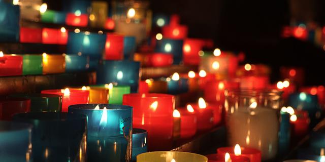 Rangées de bougies votives multicolores allumées dans une église