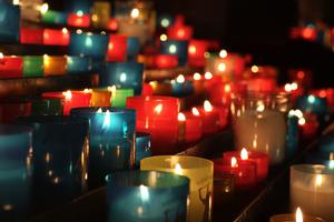 Rangées de bougies votives multicolores allumées dans une église