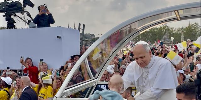 Le pape Léon XIV bénit un bébé présenté par une bénévole lors de son arrivée place de la Concorde à Paris.