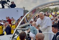 Le pape Léon XIV bénit un bébé présenté par une bénévole lors de son arrivée place de la Concorde à Paris.
